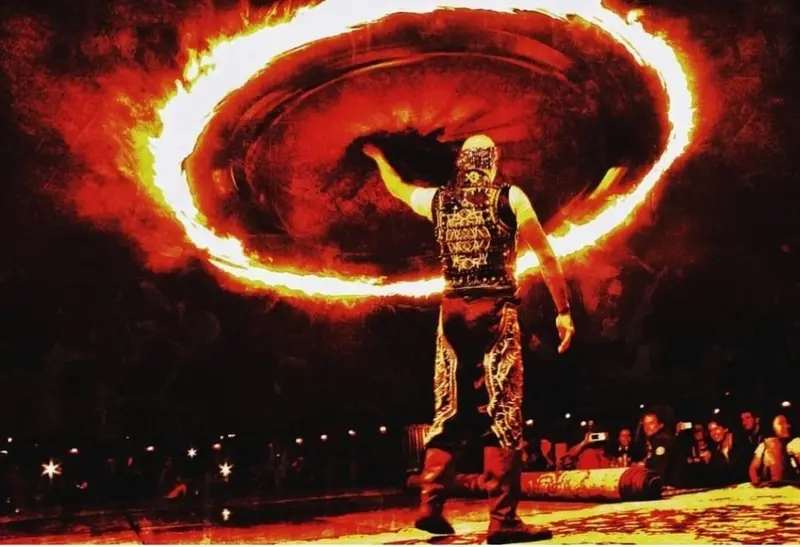 Fire tanoura dancer spinning a skirt ringed with flames at a night show