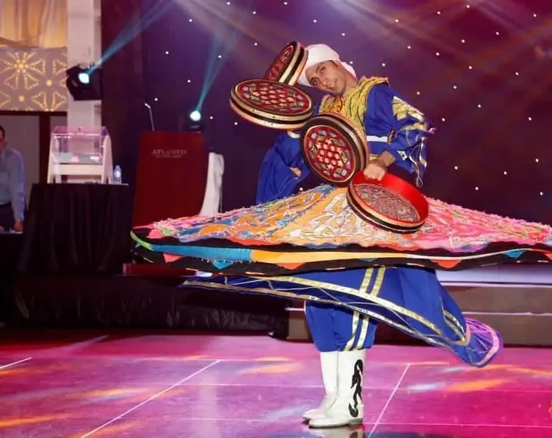 Tanoura dancer in a blue and red costume spinning a layered coloured skirt on a lit stage in Dubai